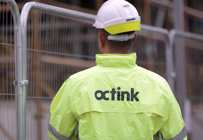 A site worker in a hiz-viz jacket with Octink printed on the back